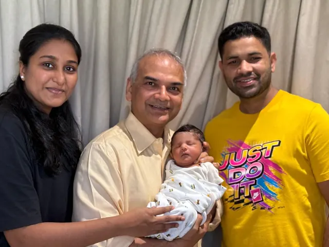 Dr. Patani holding a newborn baby with the smiling parents