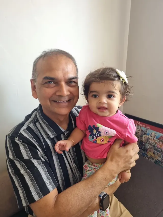Dr. Patani holding a smiling baby girl in a pink dress