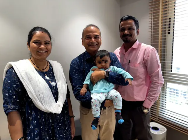 Dr. Patani holding a baby boy, with the baby's parents