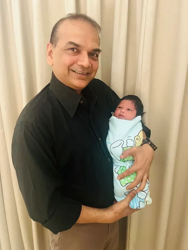 Dr. Patani cradling a newborn wrapped in a blanket