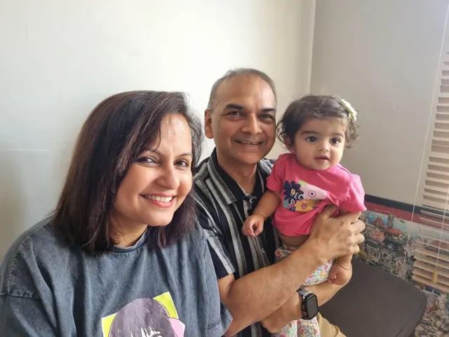 A smiling mother beside Dr. Patani, who is holding her baby girl