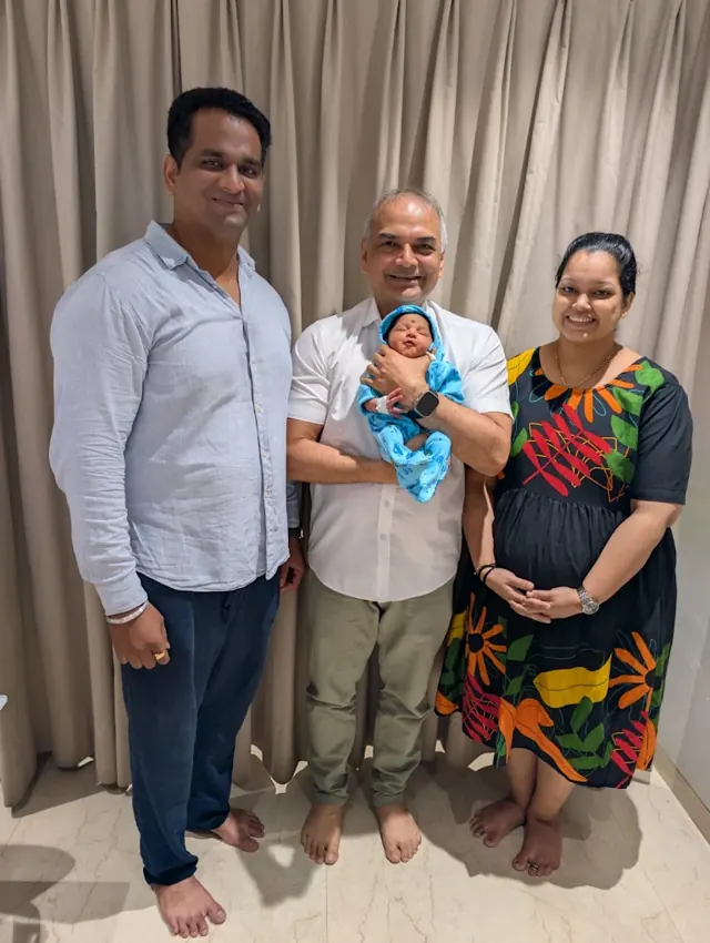 Dr. Patani holding a newborn with the parents at the clinic